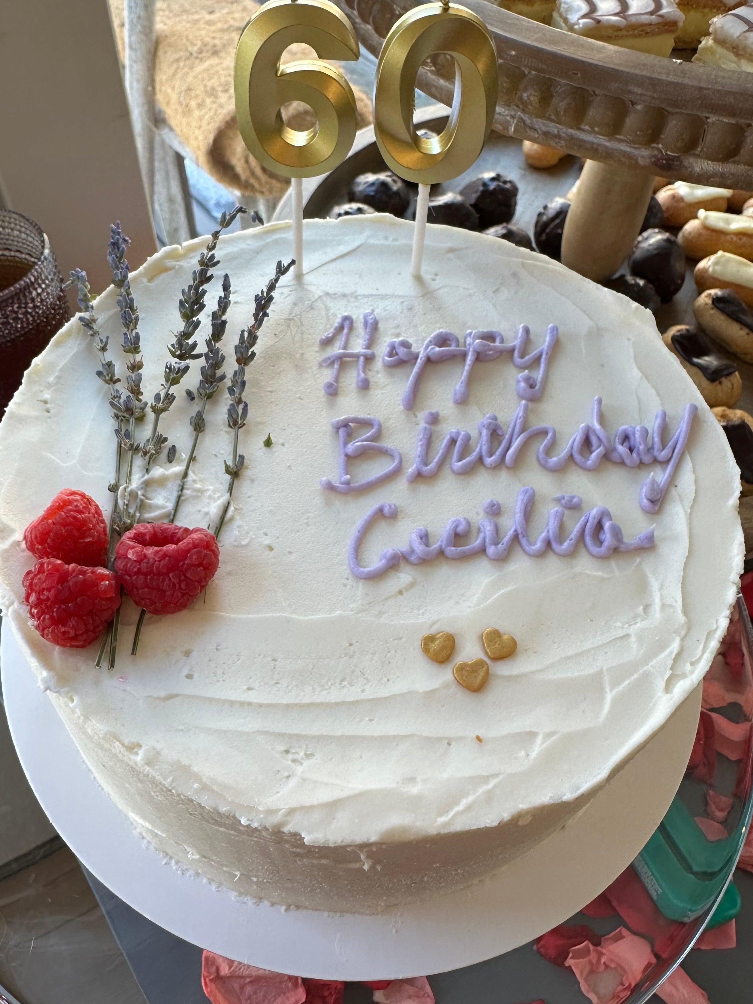 White birthday cake with 'Happy Birthday' text, berries, and number candles on a decorative plate.